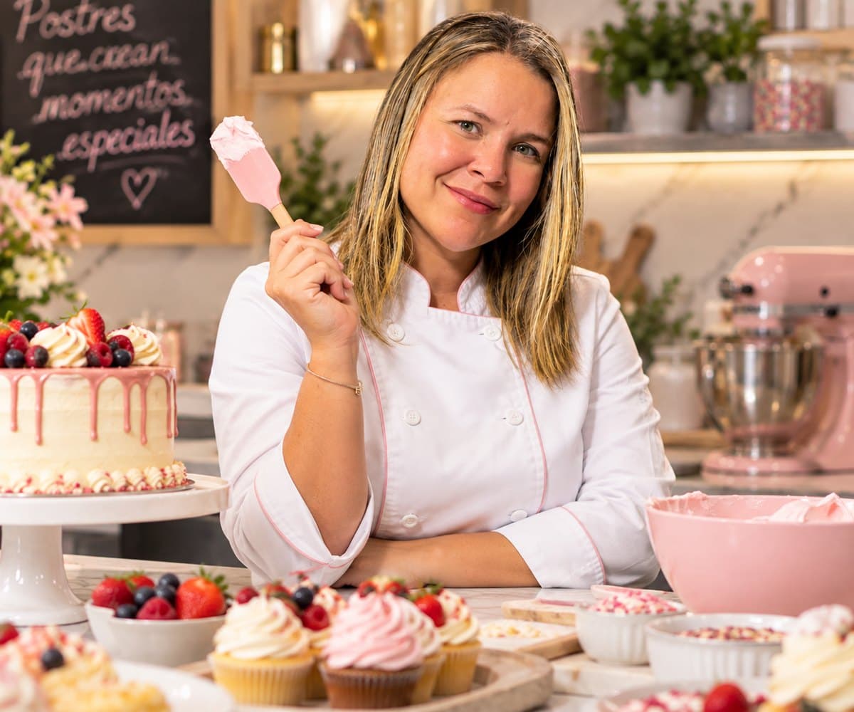 Vanessa Guanare en su cocina, con una torta y cupcakes decorados